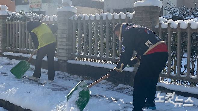 5일 오전 광주 서구 금호동에서 가파른 보행도로에 쌓인 눈을 주민들이 함께 치우고 있다. 김수진 기자