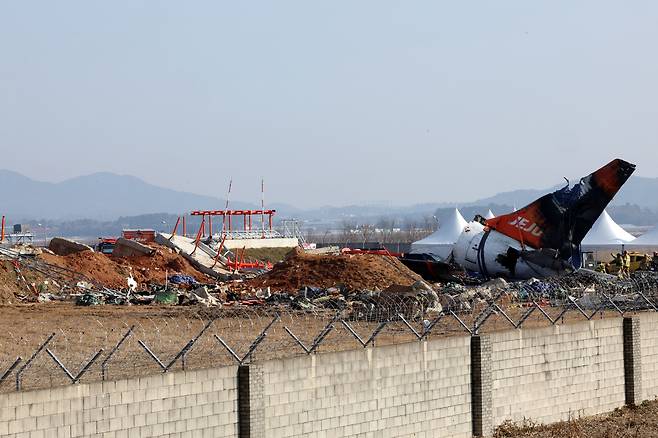 제주항공 여객기 참사 16일째인 13일 무안국제공항 사고 현장에서 소방대원들이 방수포를 걷어내고 있다. [연합]