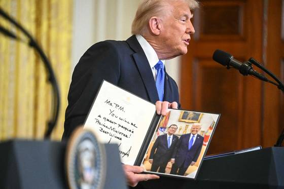 도널드 트럼프 미국 대통령이 7일(현지시각) 미국 워싱턴DC 백악관에서 진행된 이시바 시게루 일본 총리와 정상회담 후 공동 기자회견에서 함께 찍은 사진에 사인을 한 뒤 선물하고 있다. /AFPBBNews=뉴스1
