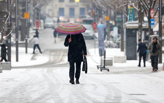 12일 눈이 내린 서울 종로구 광화문광장 인근 이면도로에서 시민들이 눈으로 덮인 길을 걷고 있다. 〈사진=연합뉴스〉