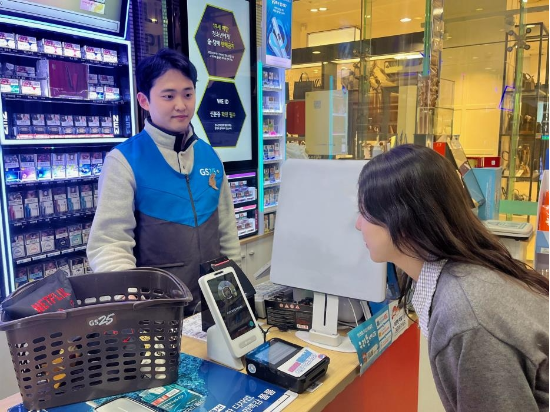GS25에서 한 직원이 토스 ‘페이스페이’로 결제하기 위해 전용 단말기에 얼굴을 비추고 시범 결제를 해보고 있다. (출처=GS25 제공)