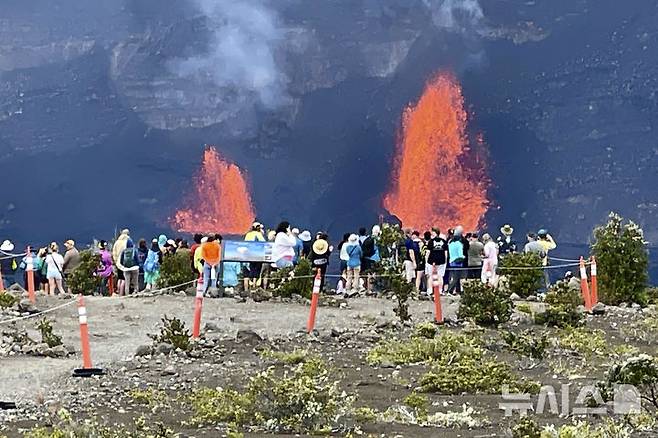 [하와이=AP/뉴시스] 15일(현지 시간) 미 하와이주 하와이섬(빅아일랜드)에서 관광객들이 용암을 분출하는 킬라우에아 화산을 구경하고 있다. 2025.01.16.