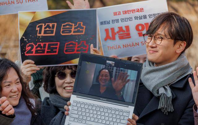 베트남 전쟁 당시 한국군의 민간인 학살 사건 생존자인 응우옌티탄(노트북 화면 속 인물)이 대한민국을 상대로 제기한 민사소송 2심 선고 공판이 열린 지난달 17일 서울 서초구 서울중앙지법 앞에서 원고 응우옌이 화상을 통해 승소 소식을 들은 뒤 기뻐하고 있다. 연합뉴스