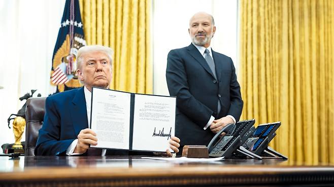 지난 13일 워싱턴 DC 백악관 집무실에서 무역 상대국이 미국 상품에 적용하는 관세율만큼 미국도 '상호 관세'를 부과한다는 내용의 행정명령에 서명하고 이를 들고 있는 도널드 트럼프(왼쪽) 대통령과 하워드 러트닉 상무장관./UPI 연합뉴스