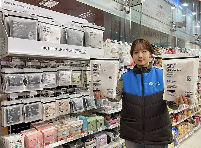 GS25 직원이 다음 달 2일 출시 예정인 GS25 전용 무신사 의류 ‘무신사 스탠다드 익스프레스’ 제품을 들고 있다. [GS25 제공]