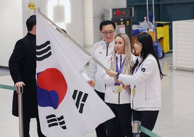 컬링 김민지, 바이애슬론 귀화선수 예카테리나 압바꾸모바가 태극기를 든 채 귀국하고 있다. 사진=연합뉴스