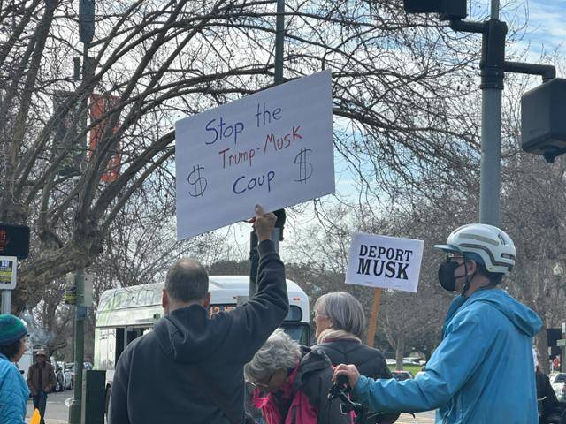17일 미국 캘리포니아주 오클랜드 시내에서 한 남성이 '트럼프-머스크 쿠데타를 멈춰라'라는 문구를 적은 팻말을 들고 있다. 도널드 트럼프 미국 대통령, 정부효율부를 이끄는 일론 머스크 테슬라 최고경영자가 미국 정부를 장악하려는 시도를 저지하자는 의미다. 오클랜드=이서희 특파원