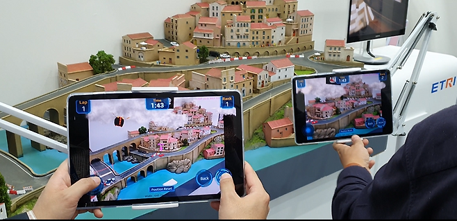 ETRI 연구진이 개발한 다중참여 원격몰입 XR기술을 활용해 자동차 레이싱 디오라마에서 레이싱을 시연하고 있다.[ETRI 제공]