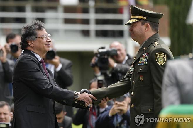 18일(현지시간) 신임 경찰청장과 악수하는 콜롬비아 대통령(왼쪽) [보고타 AP=연합뉴스. 재판매 및 DB 금지]