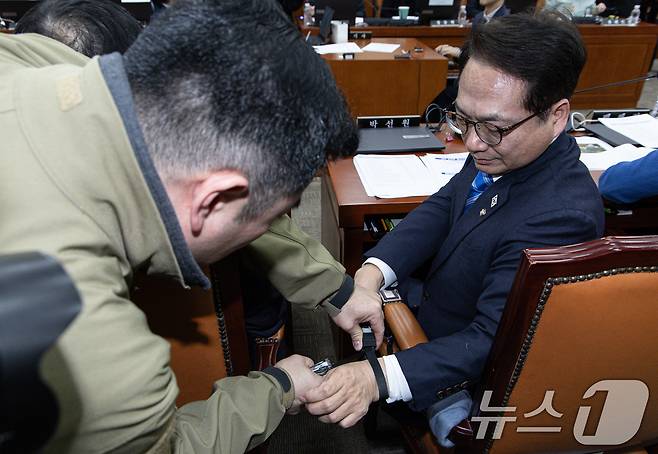 박선원 더불어민주당 의원이 21일 오전 서울 여의도 국회에서 열린 윤석열 정부의 비상계엄 선포를 통한 내란 혐의 진상규명 국정조사 제4차 청문회에서 707특임부대가 휴대한 케이블타이 수갑 관련 질의를 마친 후 보좌관의 도움을 받아 장비를 풀고 있다. 2025.2.21/뉴스1 ⓒ News1 이재명 기자