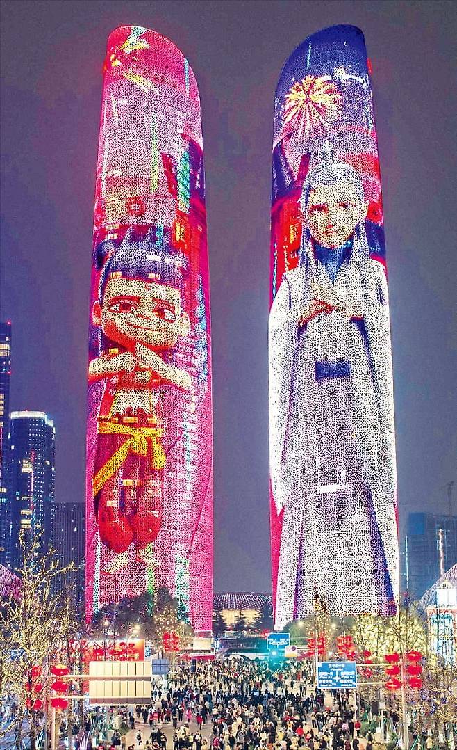 < 세계 1위 애니 등극한 ‘너자2’ > 중국 애니메이션 ‘너자2’가 개봉 20일 만에 중국에서만 2억5000만 명의 관객을 동원하면서 역대 세계 1위 애니메이션 흥행작 기록을 갈아치웠다. 중국 청두 고층 빌딩 외벽에 비친 ‘너자2’의 캐릭터 영상 아래로 사람들이 지나가고 있다. /AFP연합뉴스