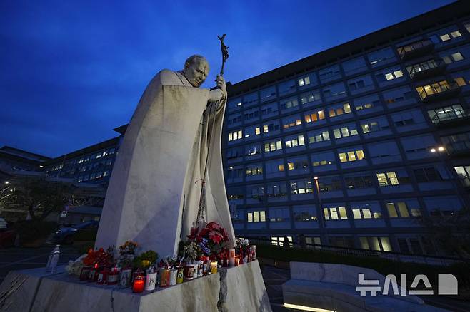 [로마=AP/뉴시스] 지난 19일(현지 시간) 이탈리아 로마의 제멜리 병원 앞에 있는 요한 바오로 2세 교황 동상 밑에 프란치스코 교황의 건강을 기원하는 촛불이 놓여 있다. 바티칸은 22일 교황이 호흡기 문제로 위독한 상태라고 발표했다. 2025.02.23.