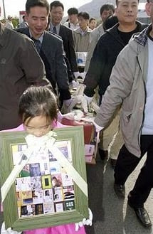 2001년 11월 3일 부악문원 앞에서 열린 이문열 작가 책 장례식. 한 어린이가 관(棺)처럼 묶은 소설책들 앞에서 '영정'을 들고 걷고 있다. 영문도 모르는 어린이에게 어른들이 시킨 일이다. /조선일보DB