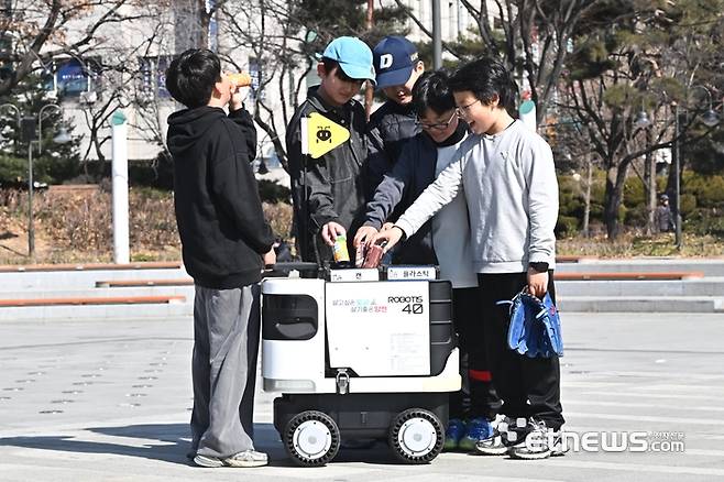 서울 양천구 파리공원에서 어린이들이 재활용품을 수거하는 로보티즈의 자율주행로봇 '개미'를 호출해 분리수거를 하고 있다.  이동근기자 foto@etnews.com