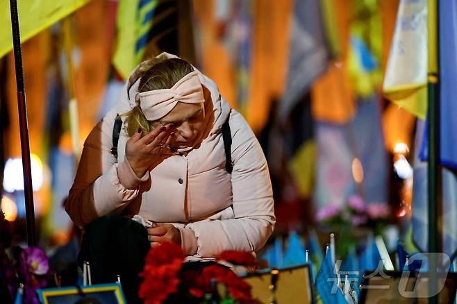 러시아의 우크라이나 침공 3주년을 맞이한 24일(현지시간) 한 여성이 우크라이나 키이우 독립광장에 설치된 전사자 추모 현장에서 눈물을 닦고 있다. ⓒ 로이터=뉴스1