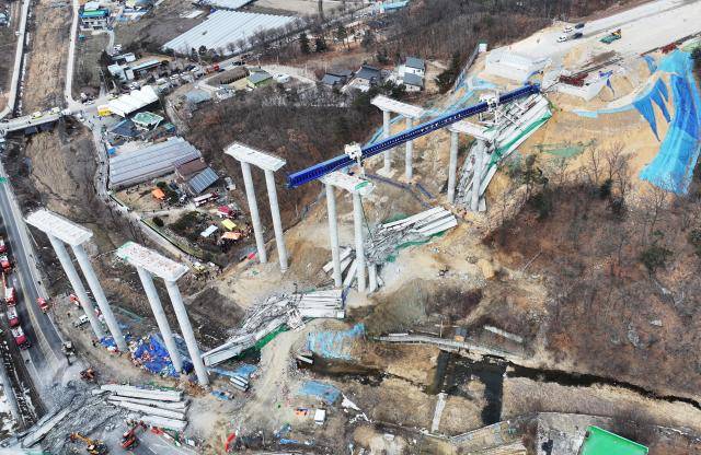 교량 보 설치 작업을 하던 대형 장비(푸른색 철골 구조물)가 교각 위에 놓여진 보 위로 주저앉아 사고가 일어난 것으로 보고 있다. 바닥에 교각에서 떨어진 교량 보 잔해물들이 보인다. 사진=연합뉴스