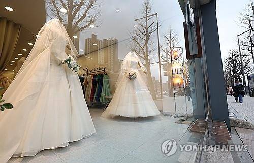 웨딩샵  (서울=연합뉴스) 류영석 기자 = 연간 혼인 건 수가 3년 연속 20만건을 밑도는 가운데 19일 서울 마포구 아현동 웨딩거리에서 한 시민이 웨딩드레스 앞을 지나고 있다. 2024.3.19 ondol@yna.co.kr
