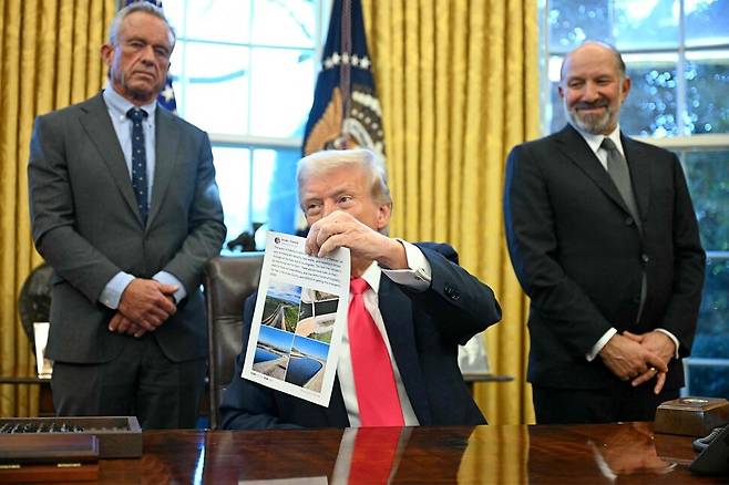 도널드 트럼프 미국 대통령이 25일 워싱턴 디시(D.C.) 백악관 집무실에서 행정명령에 서명한 뒤 기자들과 대화하면서 캘리포니아의 물 문제와 관련된 트루스 소셜 게시물을 들고 있다. 워싱턴/AFP 연합뉴스