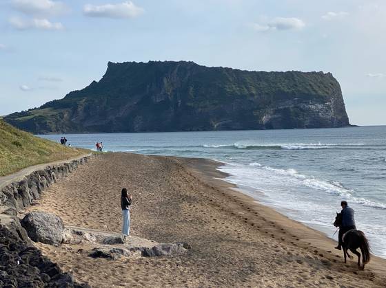 제주 성산일출봉을 배경으로 해변 승마를 즐기는 관광객. 최충일 기자