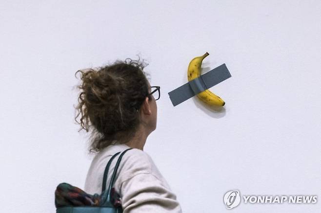 소더비 경매 전 전시된 마우리치오 카텔란의 작품 '코미디언'을 살펴보는 관람객 [사진=연합]