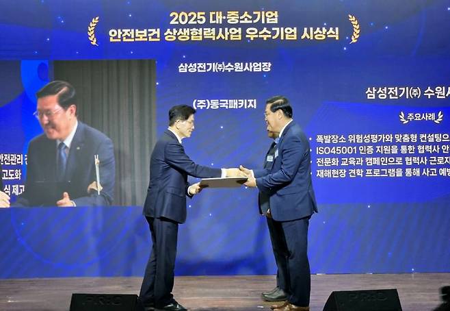 삼성전기 임승용 글로벌안전센터장(오른쪽)이 지난 26일 서울 중구 은행회관에서 열린 고용노동부 장관 주관 ‘2025년 대·중소기업 안전보건 상생협력사업’ 참여기업 협약식에서 고용노동부 김문수 장관으로부터 선정서를 받고 있다.삼성전기 제공