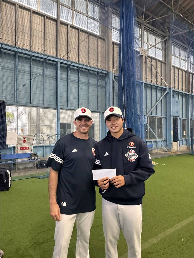 두산베어스 외국인투수 잭 로그(왼쪽)가 캠프 MVP 상금을 신인투수 홍민규에게 전달한 뒤 함께 기념사진을 찍고 있다. 사진=두산베어스