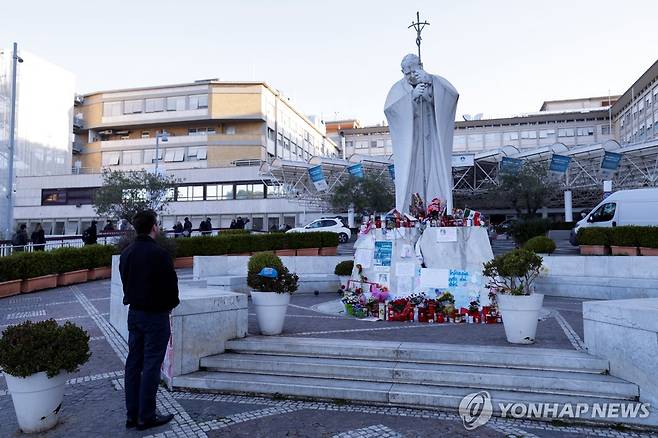 요한 바오로 2세 동상 앞에서 프란치스코 교황 쾌유 기원하는 한 남성 [로이터 연합뉴스 자료사진 재판매 및 DB 금지]
