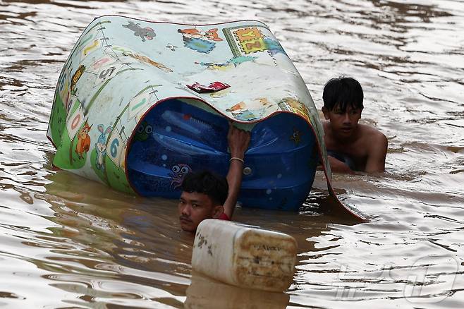 4일(현지시간) 인도네시아 자카르타에서 폭우가 내린 후 침수된 주택가에서 남성들이 물속을 걸어가고 있다. 2025.3.6 ⓒ 로이터=뉴스1