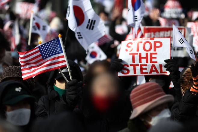 ▶지난 1월 7일 서울 한남동 대통령 관저 앞에서 성조기를 들고 탄핵 무효를 외치는 시민들. 피켓에 적힌 'STOP THE STEAL'은 미국에서 트럼프 지지자들이 2020년 대선이 부정선거라고 외치며 사용했던 문구다. (출처:연합)