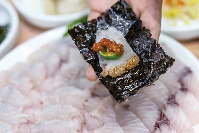 김 위에 삼치회 한 점을 올려 싸서 먹는다.