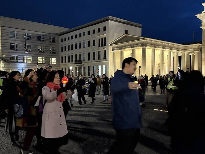 지난 14일(현지시각) 브란덴부르크 광장 앞에서 열린 시국집회에서 노래에 맞춰 둥근 원을 그리며 강강술래를 하고 있는 교민들. 국내 집회에서도 많이 불렸던 소녀시대의 ‘다시 만난 세계’를 시작으로 ‘임을 위한 행진곡’과 ‘아침이슬(양희은)’, ‘타는 목마름으로(고 김광석)’, ‘바위처럼(송강호)’, ‘함께 가자 우리 이 길을’ 등을 함께 불렀다. 사진 장예지 특파원