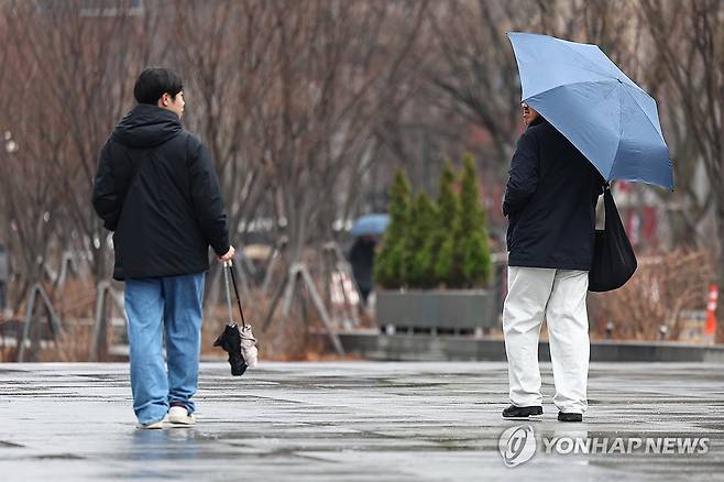 견해의 차이 (서울=연합뉴스) 서대연 기자 = 약한 비가 내리며 흐린 날씨를 보인 16일 서울 종로구 광화문 광장에서 우산을 쓴 시민과 우산을 접어 손에 든 시민이 서로를 바라보고 있다. 2025.3.16 dwise@yna.co.kr