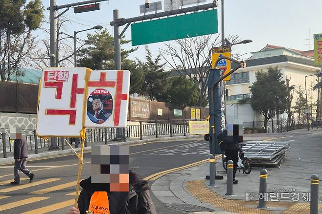 13일 오전 서울 종로구 헌법재판소 인근 재동초등학교 앞으로 탄핵 각하 팻말을 든 탄핵 반대 집회 참가자가 지나가고 있다. 김도윤 기자.