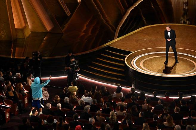 2일(현지시간) 미국 캘리포니아 할리우드 돌비 극장에서 열린 제97회 아카데미 시상식 무대에서 미국 코미디언이자 진행자인 코난 오브라이언(오른쪽)이 미국 배우 아담 샌들러(파란색 스웨트셔츠)와 이야기를 나누고 있다. (사진=AFP).