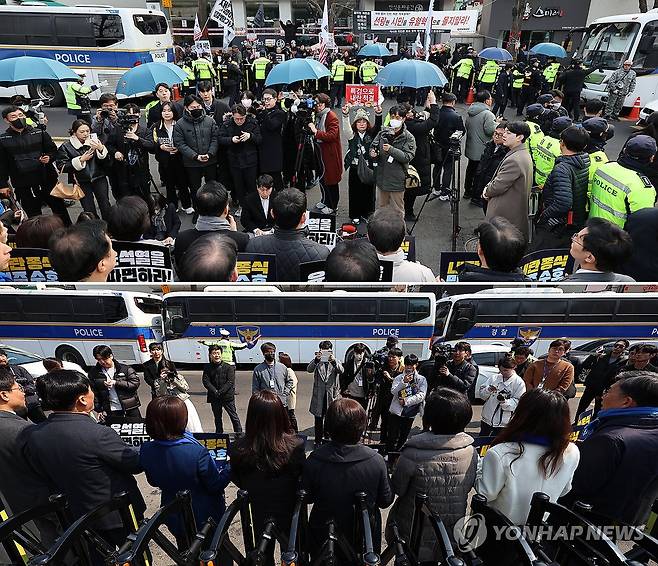 헌재 맞은편도 경찰 차벽 설치 (서울=연합뉴스) 김도훈 이진욱 기자 = 20일 오전 헌재 정문 앞에서 윤석열 대통령 파면 촉구 기자회견을 하는 민주당 의원들 맞은편에 윤석열 대통령 지지자들이몰려 있다(위). 이때 발생한 '계란 투척 사건'으로 경찰은 현재 입구 맞은편에도 경찰 버스를 추가로 주차해 차 벽을 세웠다. 2025.3.20 superdoo82@yna.co.kr