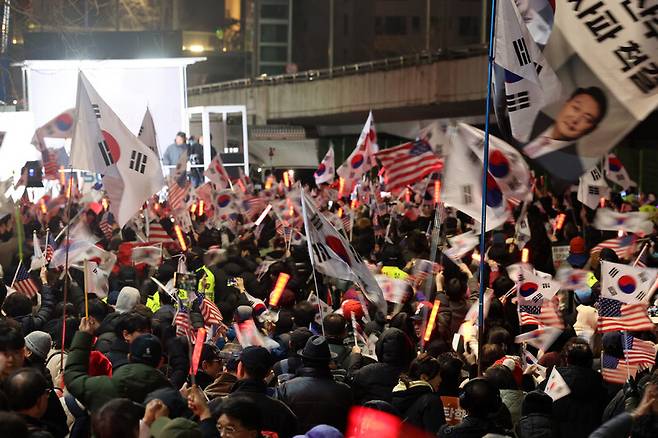 윤석열 대통령이 서울구치소에서 석방된 지난 8일 저녁 윤 대통령 지지자들이 서울 용산구 관저 들머리에서 열린 집회에 참석해 태극기와 성조기를 흔들고 있다. 김영원 기자 forever@hani.co.kr
