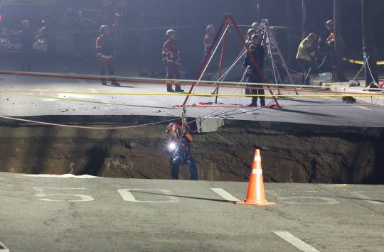 24일 싱크홀(땅 꺼짐) 사고가 발생한 서울 강동구 대명초등학교 인근 사거리에서 소방대원이 내부 구조 작업에 나서고 있다. 연합뉴스