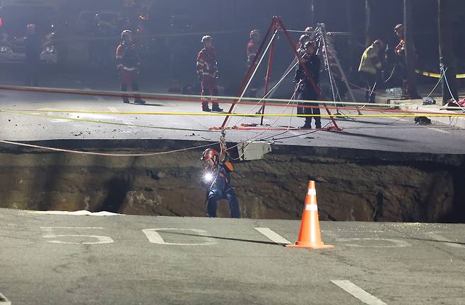 24일 싱크홀(땅 꺼짐) 사고가 발생한 서울 강동구 대명초등학교 인근 사거리에서 소방대원이 내부 구조 작업에 나서고 있다. [연합]