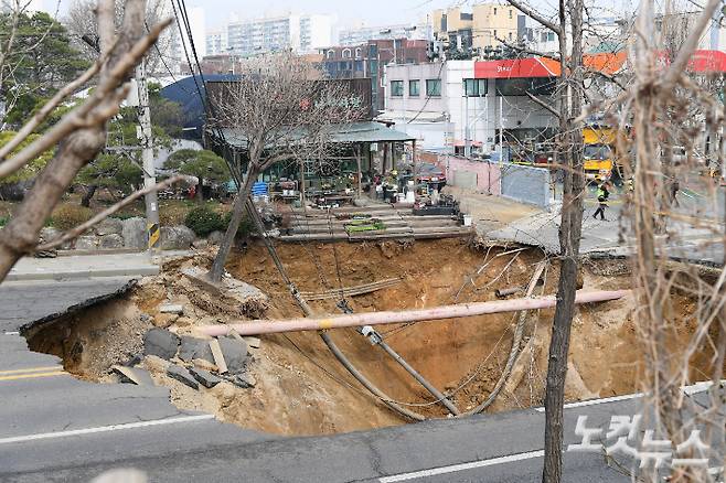 지난 24일 서울 강동구 대명초등학교 인근 사거리에서 4개차로에 걸친 '대형 싱크홀(땅꺼짐)' 이 발생했다. 25일 사고 현장 주변이 통제되고 있다. 싱크홀에는 승용차 1대와 오토바이 1대가 빠졌으며, 승용차 탑승자 1명은 인근 병원으로 이송됐다. 현재 싱크홀 아래에는 오토바이 운전자 1명이 매몰돼 있다. 깊이는 30m로 추정된다. 박종민 기자