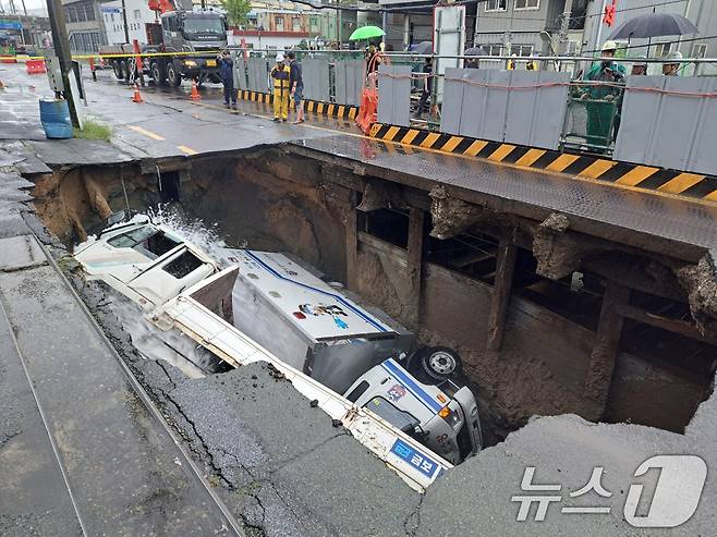 지난해 9월 21일 오전 8시45분께 부산 사상구 한 도로에서 싱크홀이 발생해 도로에서 배수 지원을 하던 삼락119안전센터 배수 차량과 5톤 트럭이 빠져있다. (부산소방재난본부 제공) 2024.9.21/뉴스1 ⓒ News1 윤일지 기자