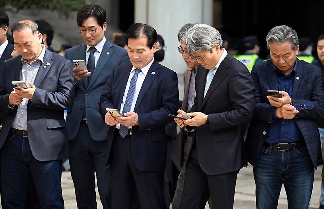 26일 오후 서울 서초구 서울고등법원에서 열린 이재명 더불어민주당 대표 공직선거법 위반 혐의 항소심 선고 공판이 열렸다. 동료 의원들이 공판이 열리는 동안 법원 외부에 모여 휴대폰으로 뉴스속보를 보고 있다.  2025.03.26. 사진공동취재단