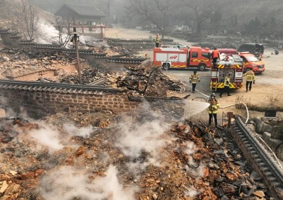 중수 작업하는 소방대원들 - 26일 경북 의성군 단촌면 고운사에서 소방대원들이 불에 탄 건물 위에 물을 뿌리고 있다. 2025.3.26 연합뉴스