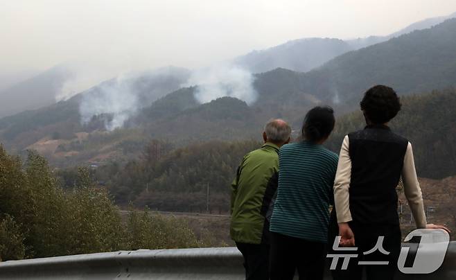 경남 산청·하동 산불 일주일째인 27일 오후 주민들이 지리산과 인접한 산청군 시천면 동당마을 위로 피어오르는 산불 연기를 지켜보고 있다. 산청에는 오후부터 5mm 내외의 적은 비가 예보됐지만 현재 비는 내리지 않고 있다. 2025.3.27/뉴스1 ⓒ News1 윤일지 기자
