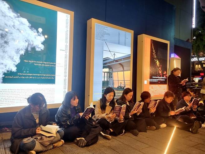 2024년 10월29일 저녁 서울 용산구 이태원역 1번 출구 인근 ‘기억과 안전의 길’에서 ‘이태원 참사 2주기를 기억하는 행동독서회’에 참여한 시민들이 참사 2주기 구술기록집 ‘참사는 골목에 머물지 않는다’를 읽고 있다. 한겨레 고나린 기자