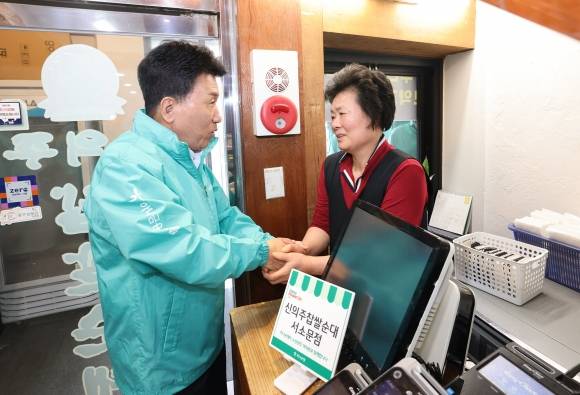 함영주 하나금융지주 회장(왼쪽)이 26일 서울 중구에 위치한 한 소상공인 사업장을 찾아 실내 보수 지원 활동을 펼친 뒤 소상공인과 두 손을 맞잡고 이야기를 나누고 있다. 하나금융 제공