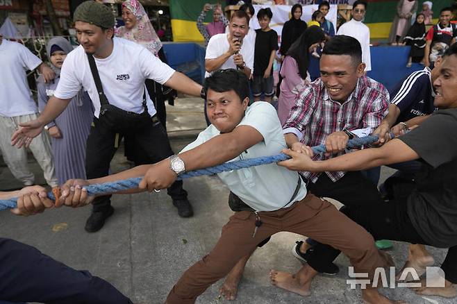 [케손시티=AP/뉴시스] 31일(현지 시간) 필리핀 케손시티의 한 공원에서 라마단을 마친 무슬림들이 줄다리기를 하며 이드 알피트르 축제를 즐기고 있다. 2025.03.31.