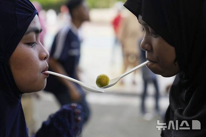 [케손시티=AP/뉴시스] 31일(현지 시간) 필리핀 케손시티의 한 공원에서 라마단을 마친 무슬림들이 플라스틱 숟가락을 입에 물고 라임을 옮기는 게임을 하면서 이드 알피트르 축제를 즐기고 있다. 2025.03.31.