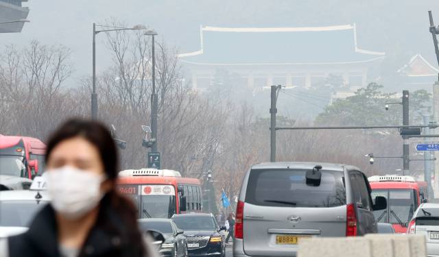 지난 25일 서울 중구의 한 대로변에서 시민들이 미세먼지를 피하기 위해 마스크를 쓰고 이동하고 있다. 뉴스1