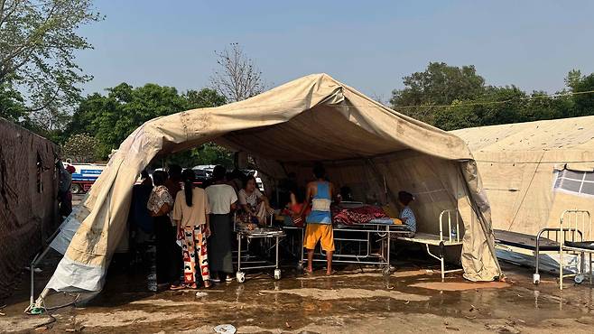 부상자들은 찌는 듯한 더위 속 네피도 내 최대 병원 밖에 설치된 임시 천막에서 치료받고 있다