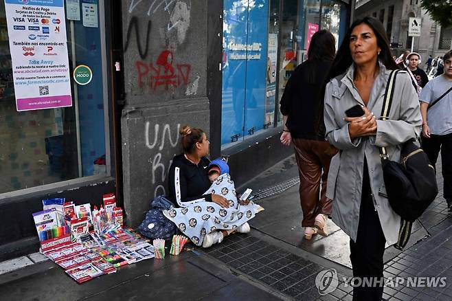 아르헨티나 거리에서 아기를 안고 물건 파는 여인 (부에노스아이레스 AFP=연합뉴스)  31일(현지시간) 아르헨티나의 수도 부에노스아이레스의 한 거리에서 아이를 팔에 안고 있는 여성이 색연필을 팔고 있다. 아르헨티나의 빈곤율은 2024년 하반기에 인구의 38.1%에 달해 52.9%를 기록한 상반기에 비해 14.8% 포인트 급격히 감소했다고 아르헨티나 국립통계청(Indec)이 발표했다. 2025.4.1 photo@yna.co.kr